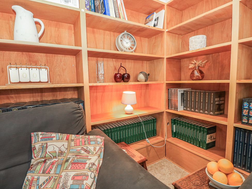 A snug area with a sofa, bookshelves, and a lamp at The Bookshop Apartment in Cowes