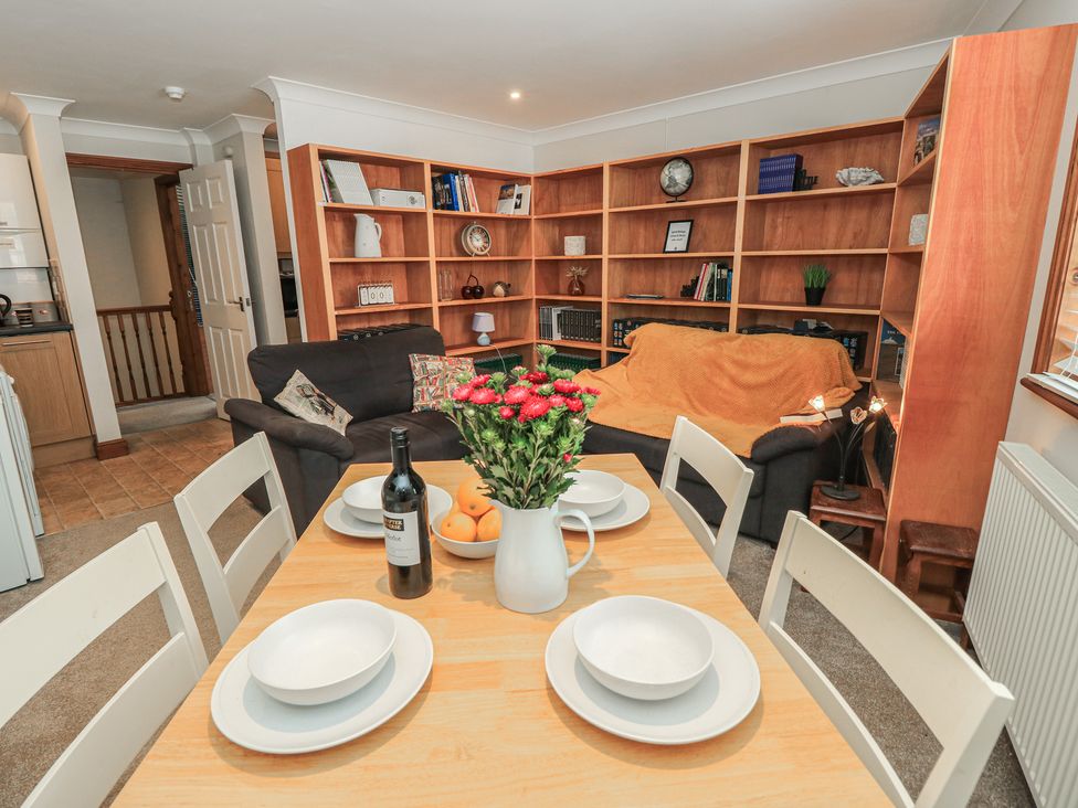 A dining area with a table, chairs, and a sofa at The Bookshop Apartment in Cowes