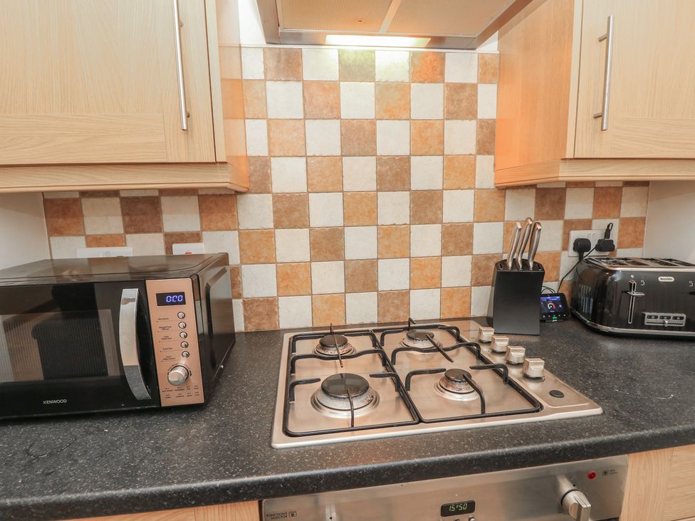 A kitchen with a gas stove and microwave at The Bookshop Apartment in Cowes