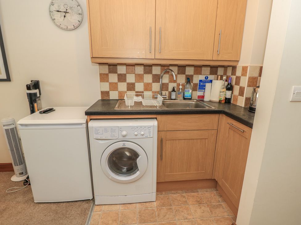 A kitchen with a fridge, washing machine, and sink at The Bookshop Apartment in Cowes