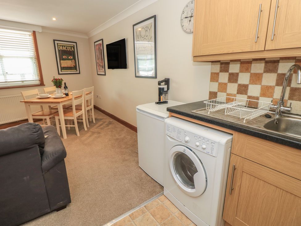 A kitchen with washing machine and dining area at The Bookshop Apartment in Cowes