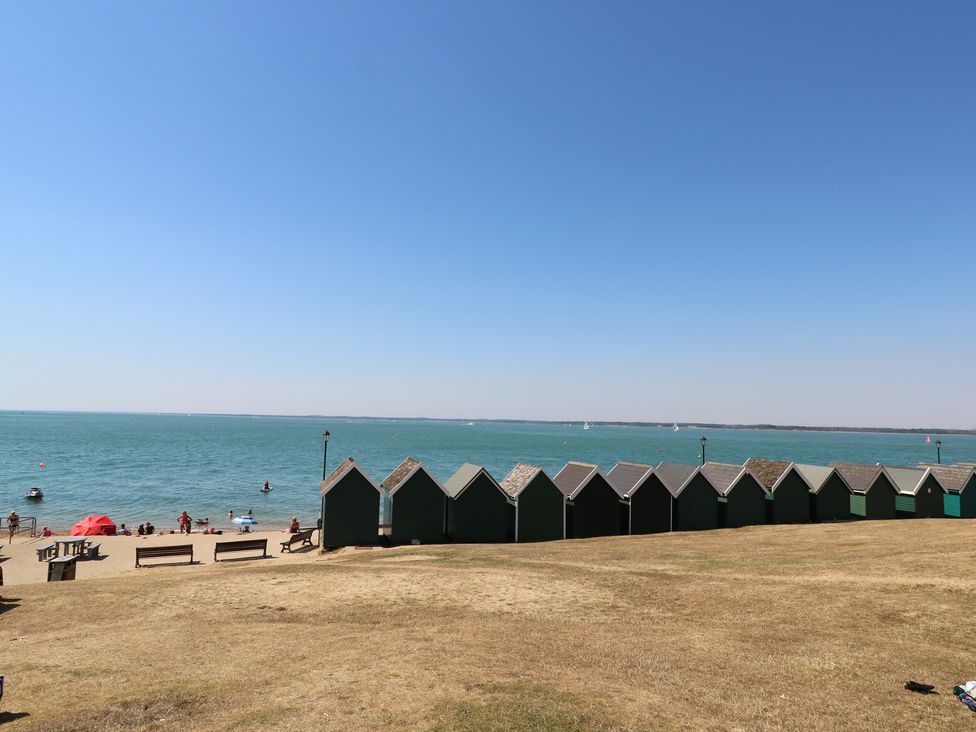 A beach with beach huts and people near the water at The Bookshop Apartment in Cowes