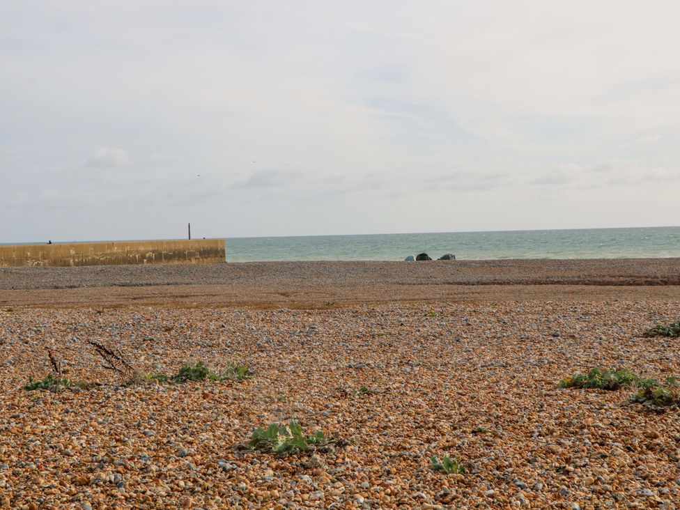 A beach with pebbles and a pier extending into the sea at 67a Harbour Way Shoreham-by-Sea
