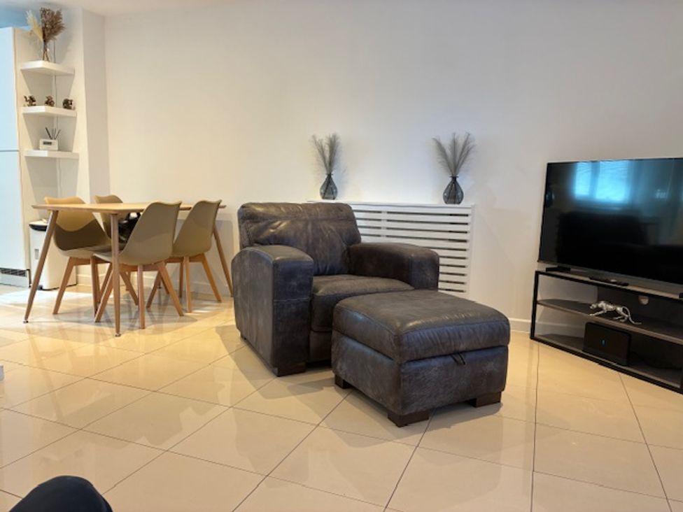 A living room with an armchair and a dining table at Harbour Way in Shoreham-By-Sea