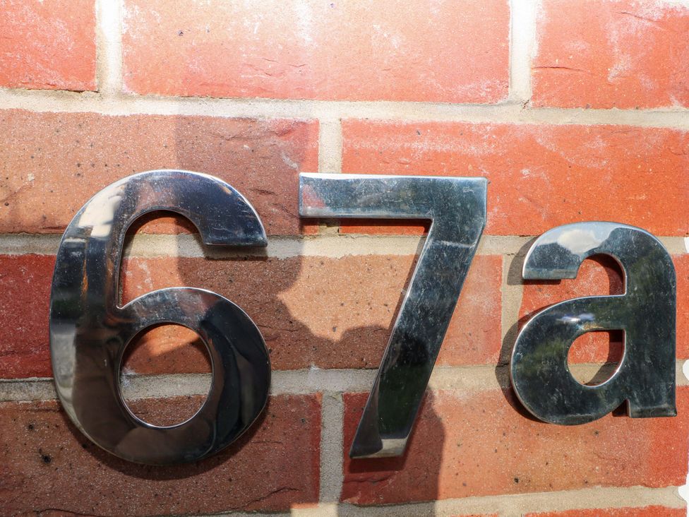 A house number sign reading 67a on a brick wall at Harbour Way in Shoreham-By-Sea