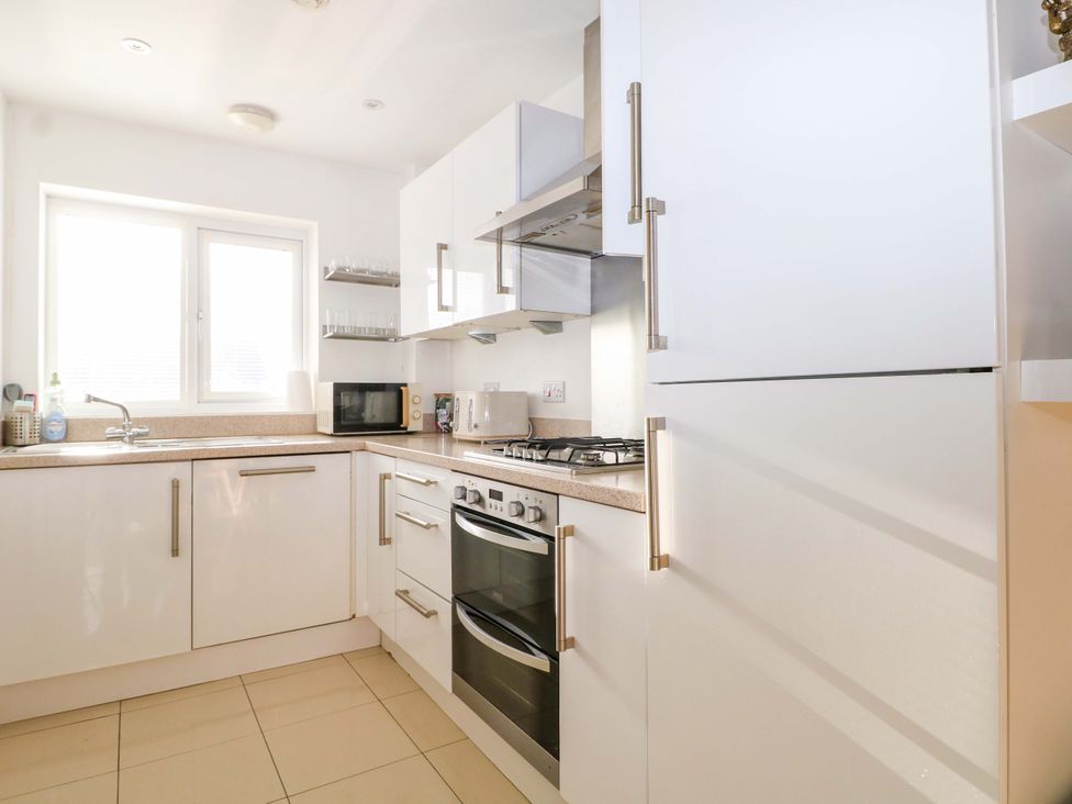 A kitchen with a sink, countertop, microwave, stove, and refrigerator at Harbour Way Shoreham-By-Sea