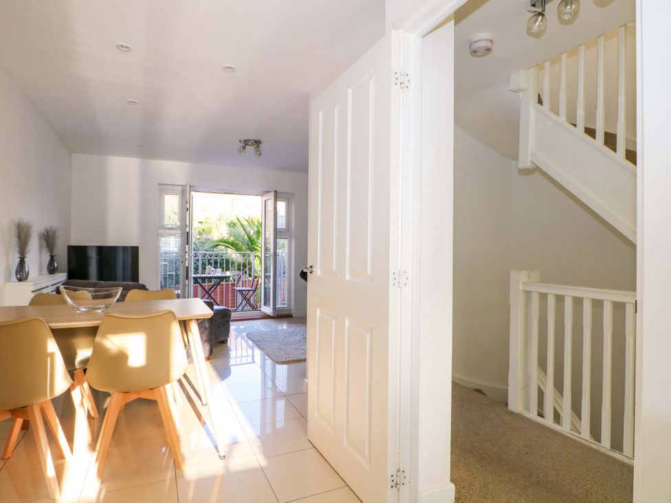 A dining room with a table and chairs looking towards an open door at Harbour Way Shoreham-By-Sea