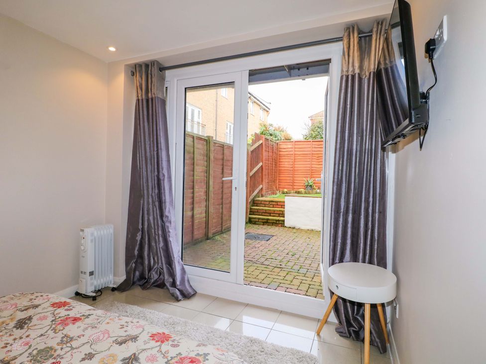 A bedroom with double doors leading to a garden at Harbour Way in Shoreham-By-Sea