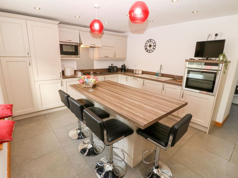 A kitchen with a table and stools at The Old Barn in Pwllheli