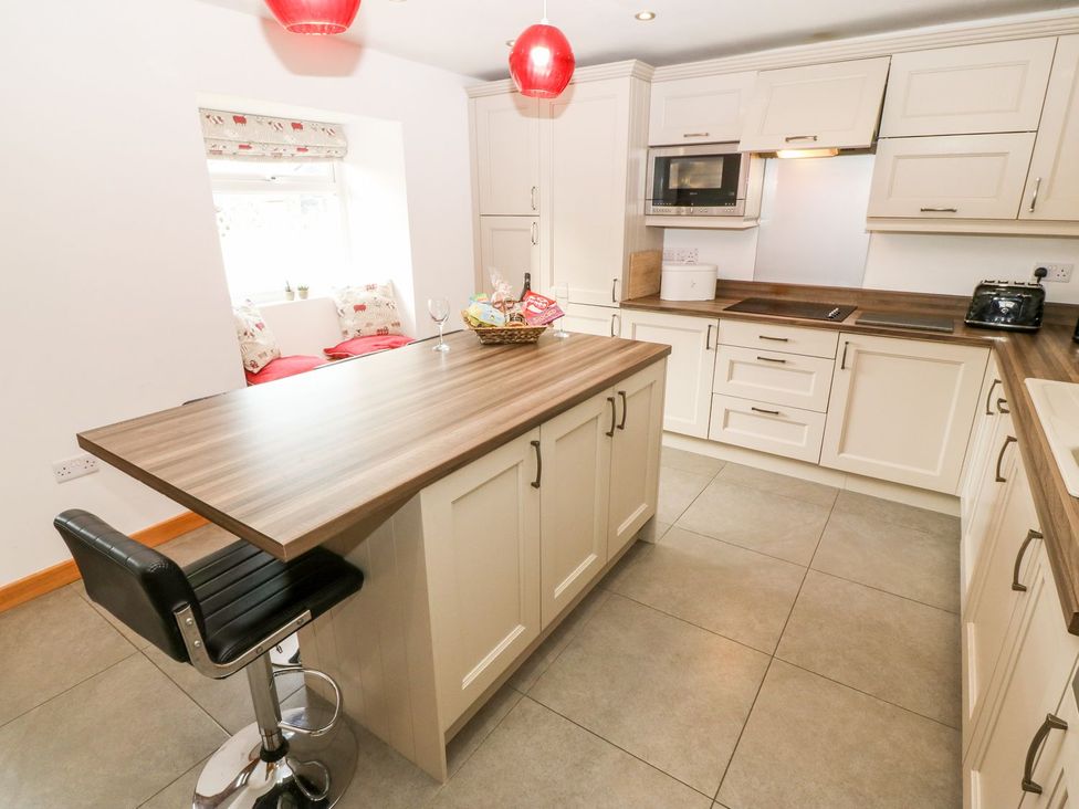A kitchen with a worktop and bar stool at The Old Barn in Pwllheli