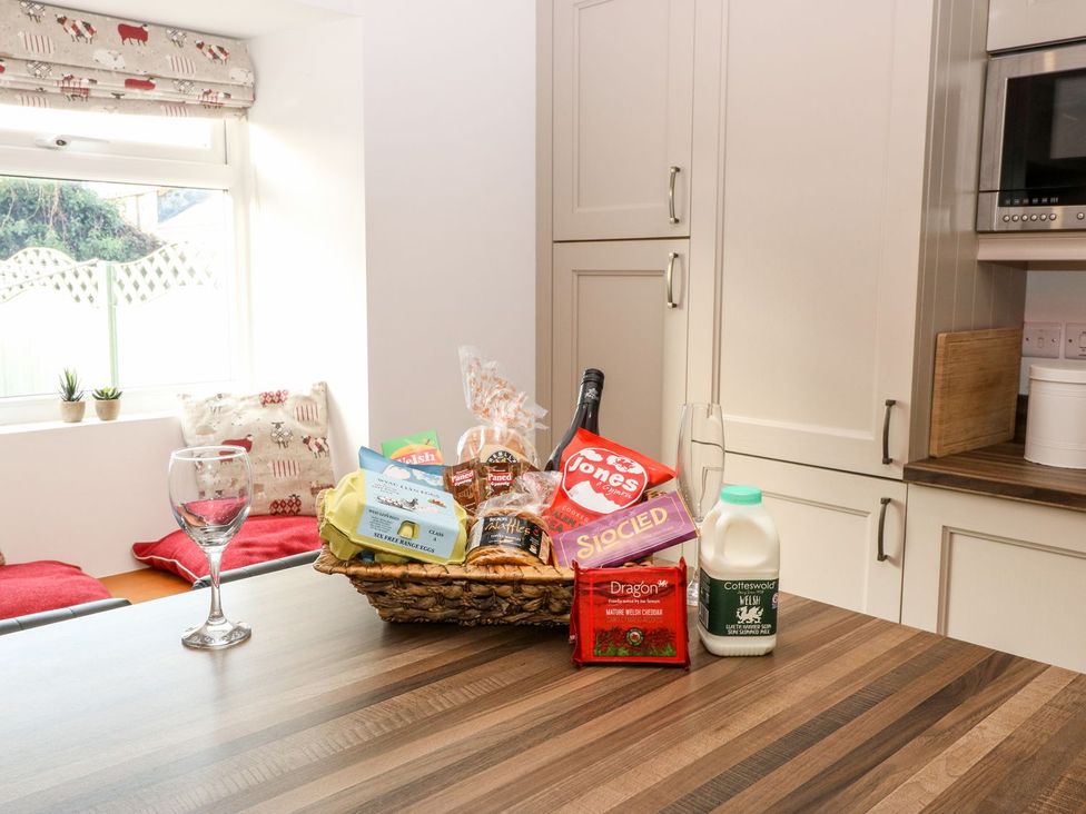 A kitchen with a basket of food and a glass on the table at The Old Barn in Pwllheli
