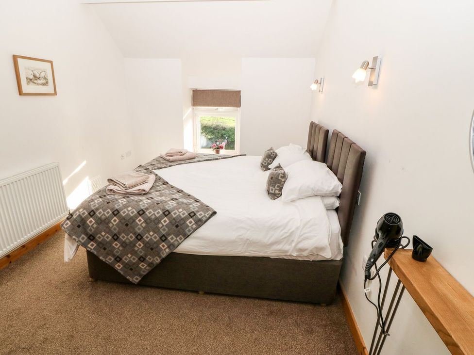 A bedroom with a bed and window at The Old Barn in Pwllheli