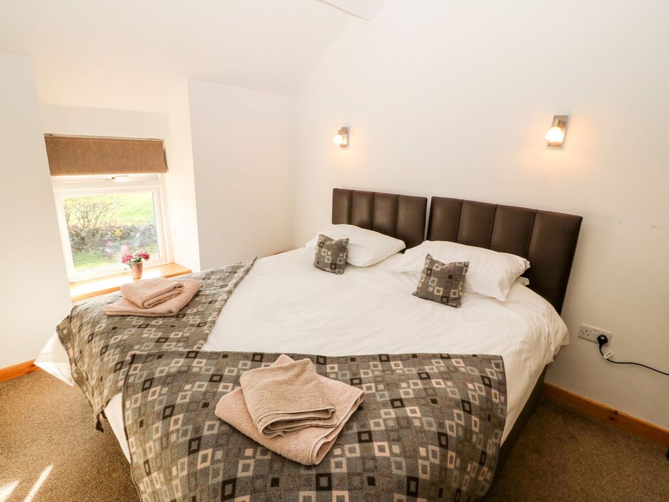 A bedroom with a bed and window at The Old Barn in Pwllheli