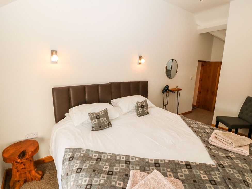 A bedroom with a bed and a mirror at the property in Pwllheli