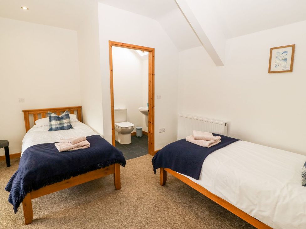 A bedroom with two beds and an ensuite bathroom at The Old Barn in Pwllheli