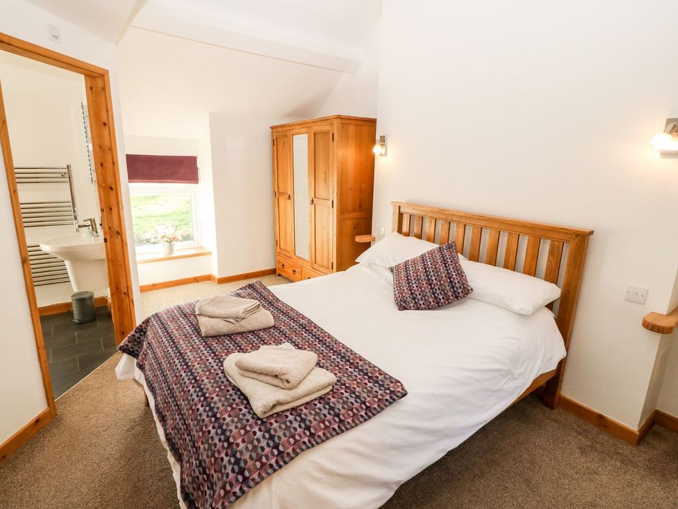 A bedroom with a bed and wardrobe at The Old Barn in Pwllheli