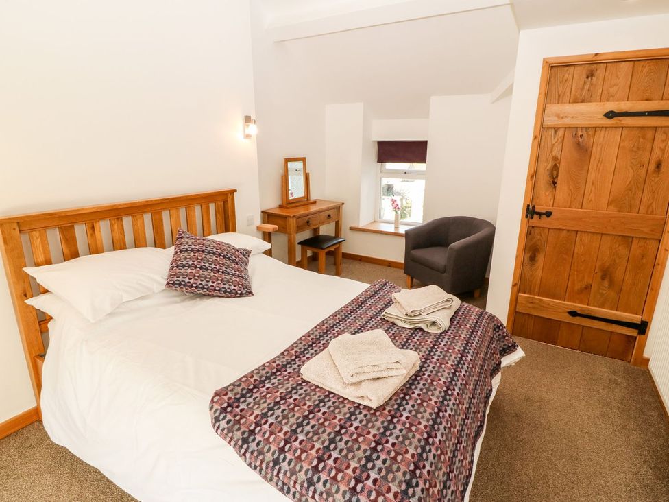 A bedroom with a bed and wooden furniture at The Old Barn in Pwllheli