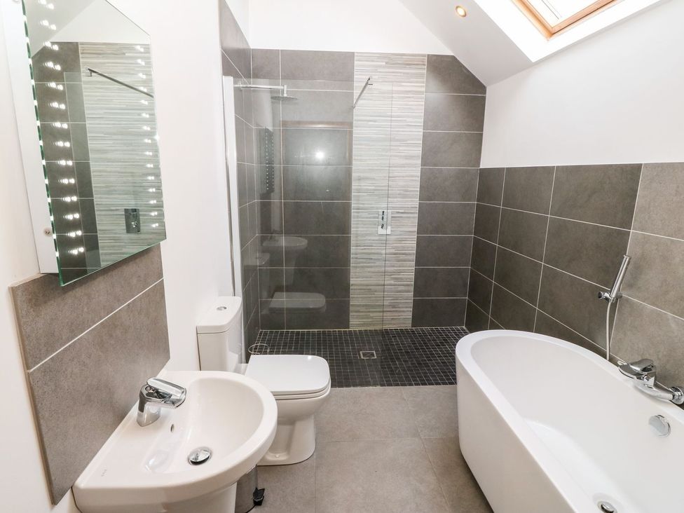 A bathroom with shower and bathtub at The Old Barn in Pwllheli