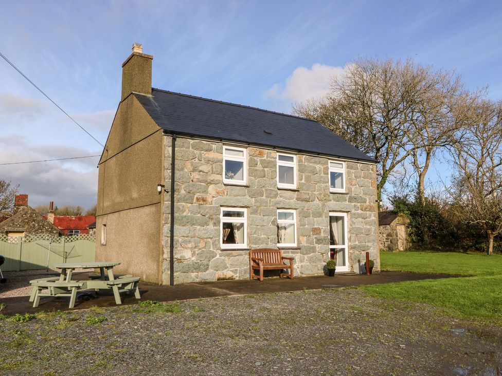 A house with windows and a bench in front at Pwllheli