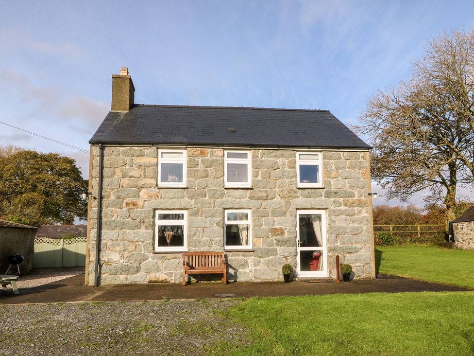 A house with a bench in front and trees at the side in Pwllheli