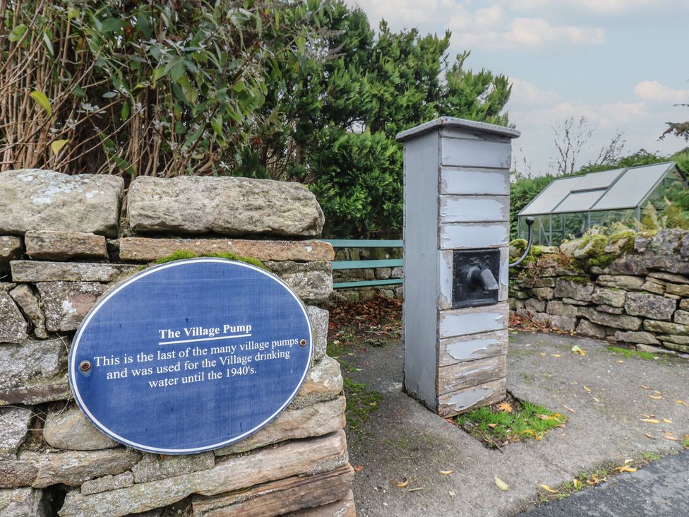 A village pump with a sign and stone wall at Daleholme in Barnard Castle