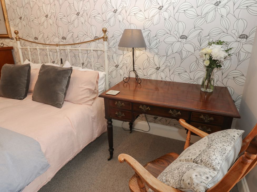 A bedroom with a bed, table, lamp, and chair at Daleholme in Mickleton, Teesdale