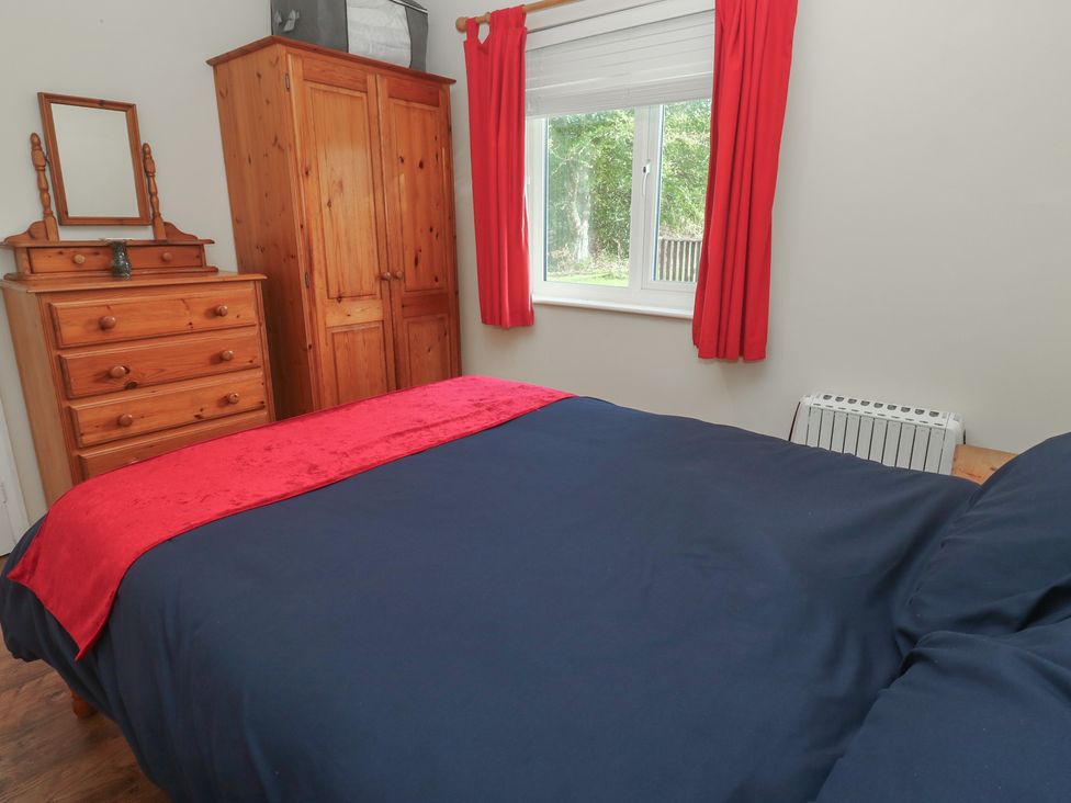 A bedroom with a bed and wooden furniture at Little Egret - Number 2