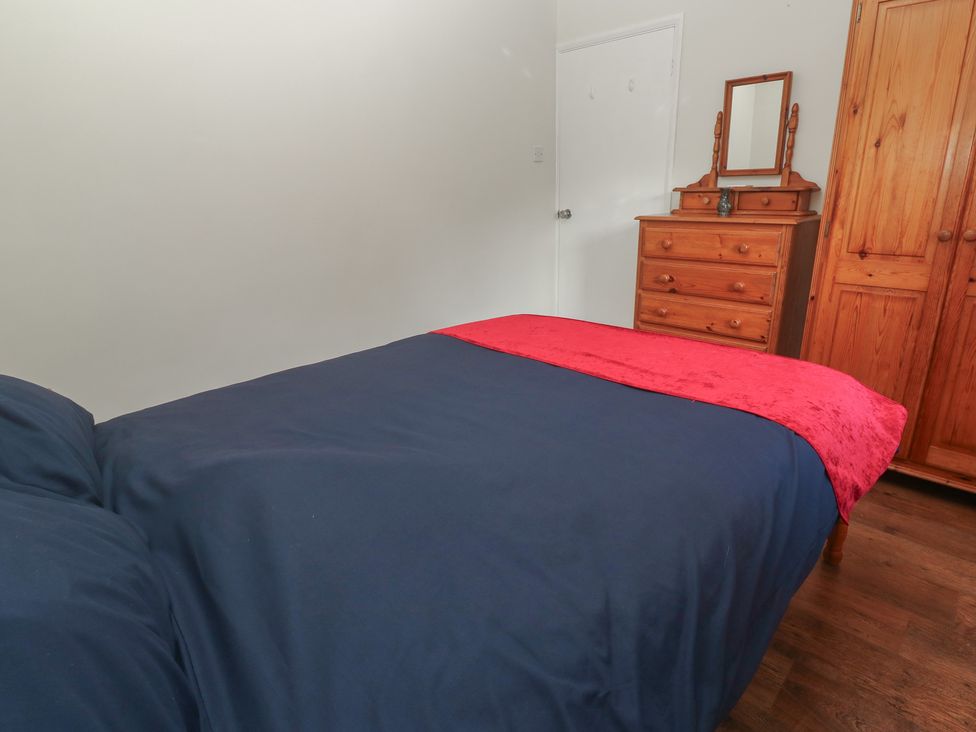 A bedroom with a bed and wooden furniture at Little Egret - Number 2