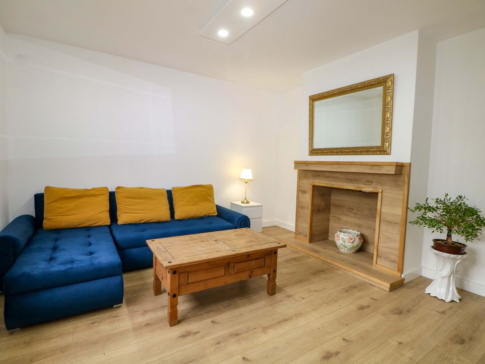 A living room with a blue sofa and wooden coffee table at 7 Oaks Track in Carshalton