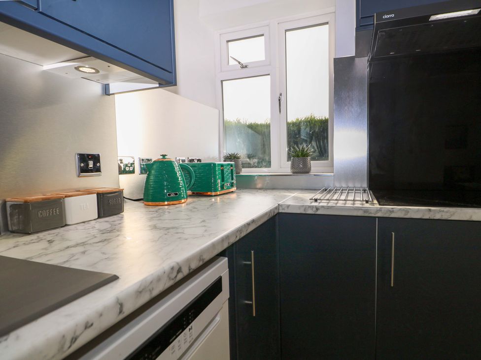 A kitchen with marble countertop and green kitchen utensils at 7 Oaks Track in Carshalton