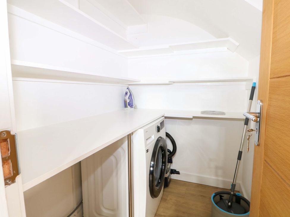 A laundry room with a washing machine and shelves at 7 Oaks Track in Carshalton