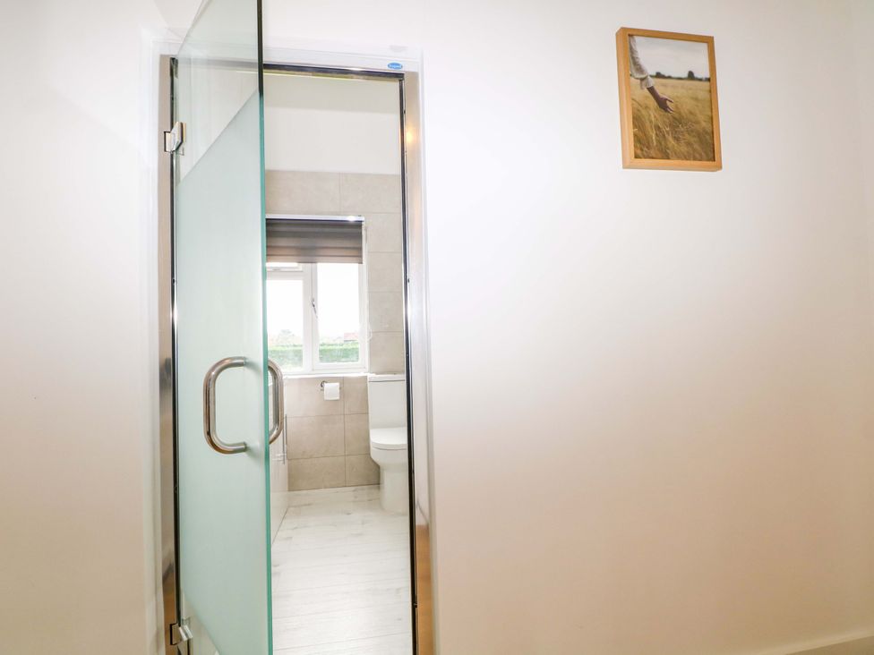A bathroom with a glass shower door and toilet at 7 Oaks Track in Carshalton