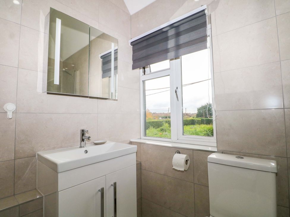 A bathroom with a sink, toilet, and window at 7 Oaks Track in Carshalton