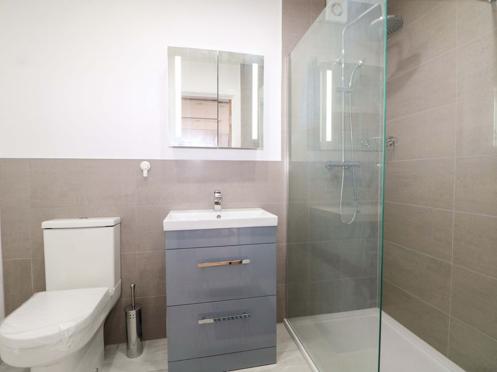 A bathroom with a shower, toilet, sink, and mirror at 7 Oaks Track in Carshalton