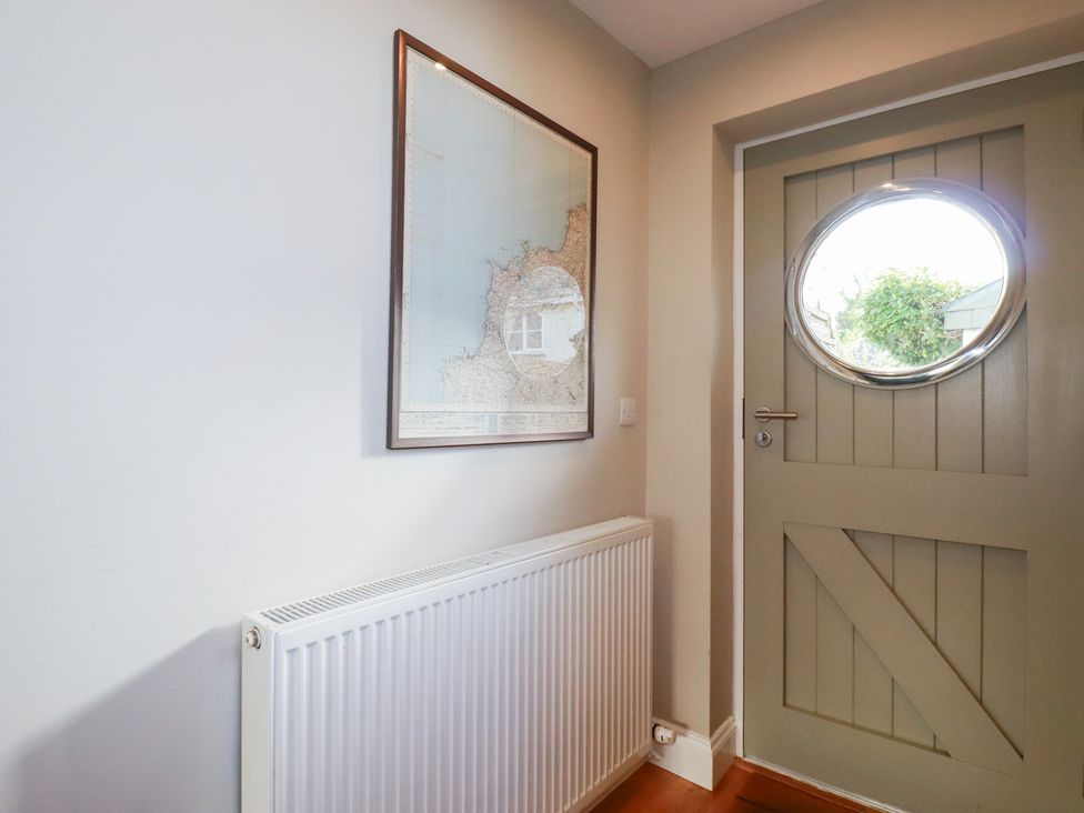 A hallway featuring a map on the wall and a round door at The Mizzen St Endellion near Port Isaac