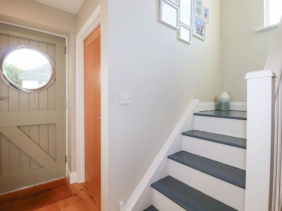A hallway with a staircase and a door at The Mizzen in St Endellion near Port Isaac