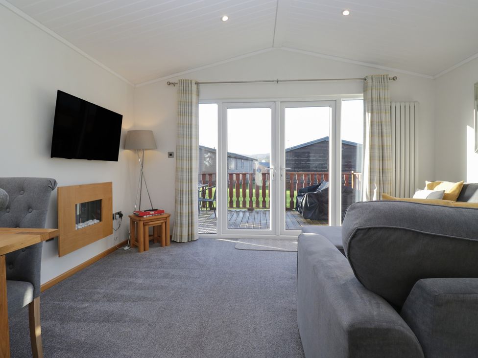 A living room with television and sofa at Bluebell Lodge in Warton