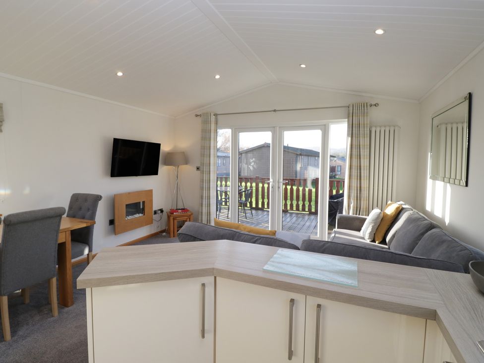 A living room with a sofa and dining area at Bluebell Lodge in Warton
