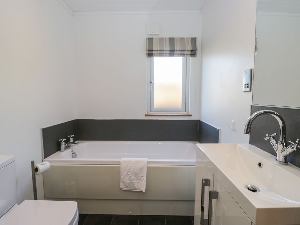 A bathroom with a bathtub, toilet, and sink at Bluebell Lodge in Warton