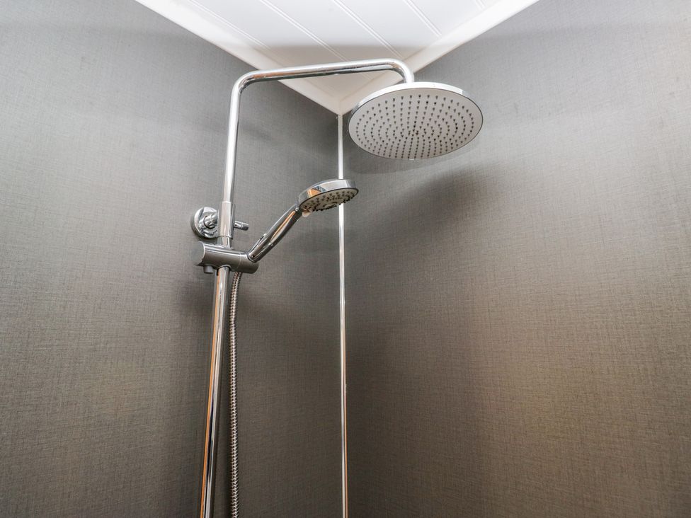 A shower with a rain showerhead and handheld shower fixture at Bluebell Lodge in Warton
