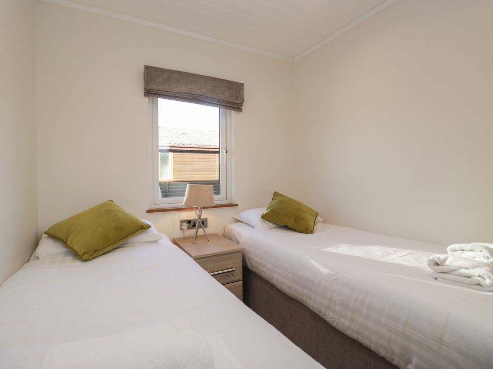 A bedroom with twin beds and a bedside table at Bluebell Lodge in Warton