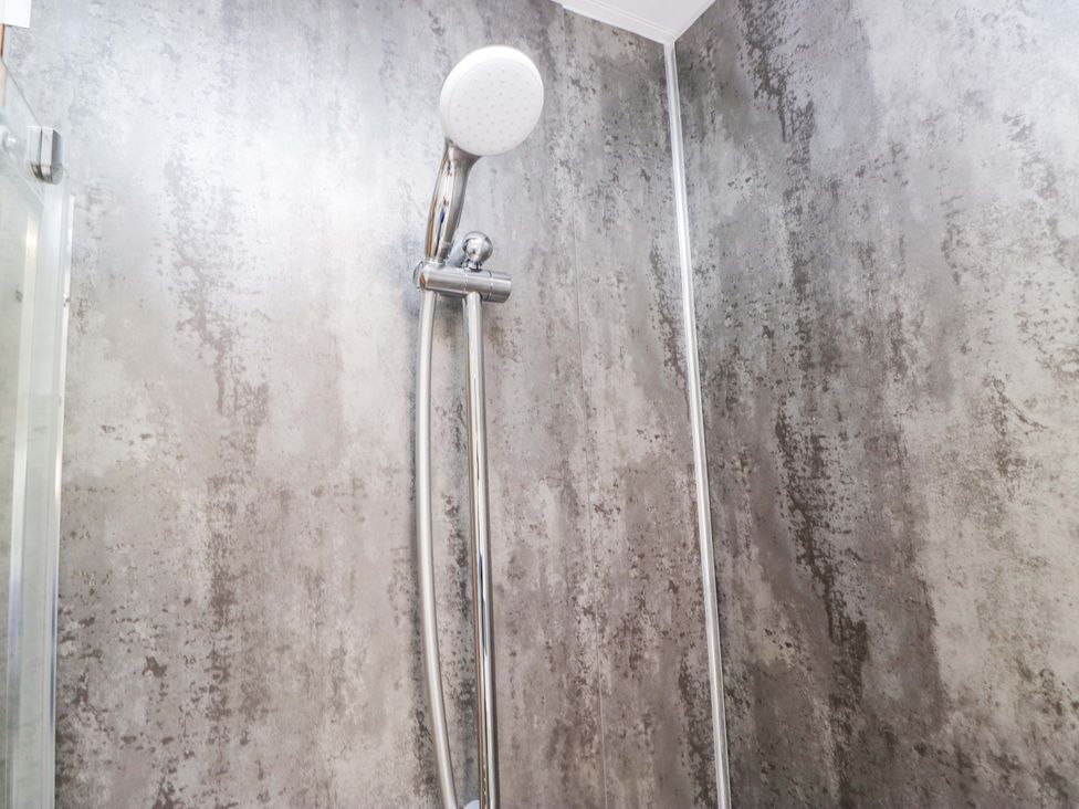 A shower with a showerhead and wall at Bluebell Lodge in Warton