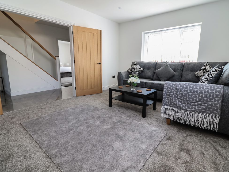 A living room with a sofa, coffee table, and rug at 1 Talbot Drive Talacre