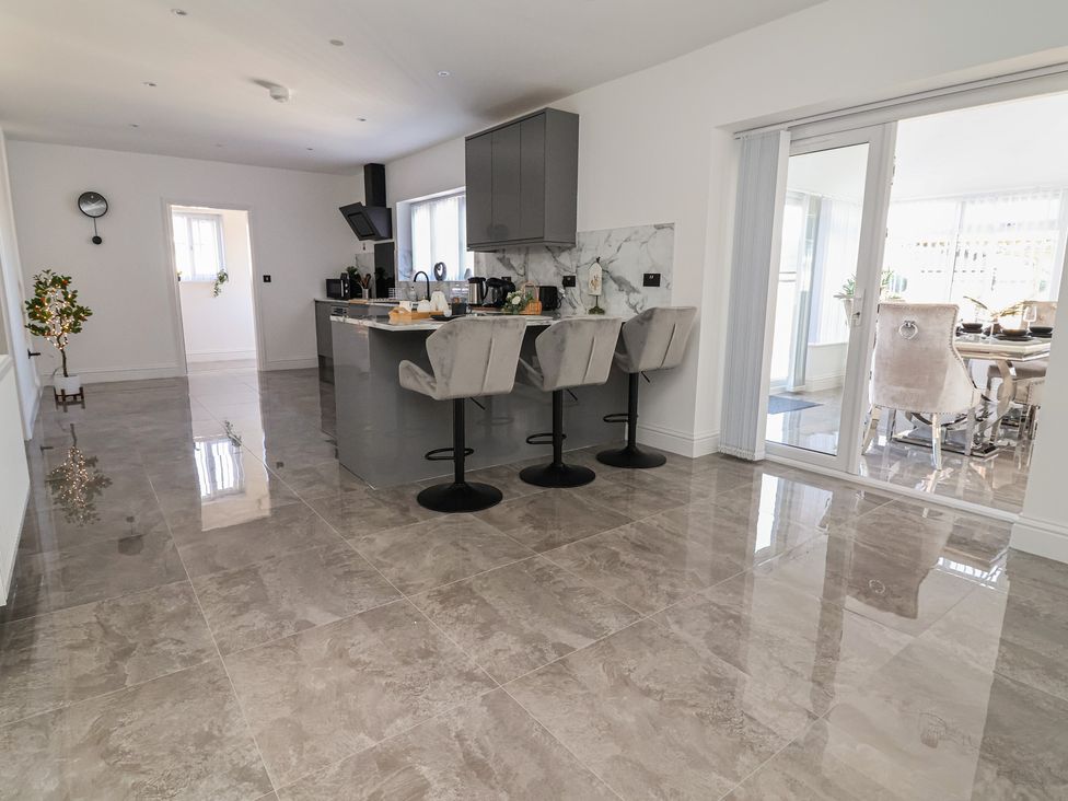A kitchen with an island and bar stools at 1 Talbot Drive Talacre
