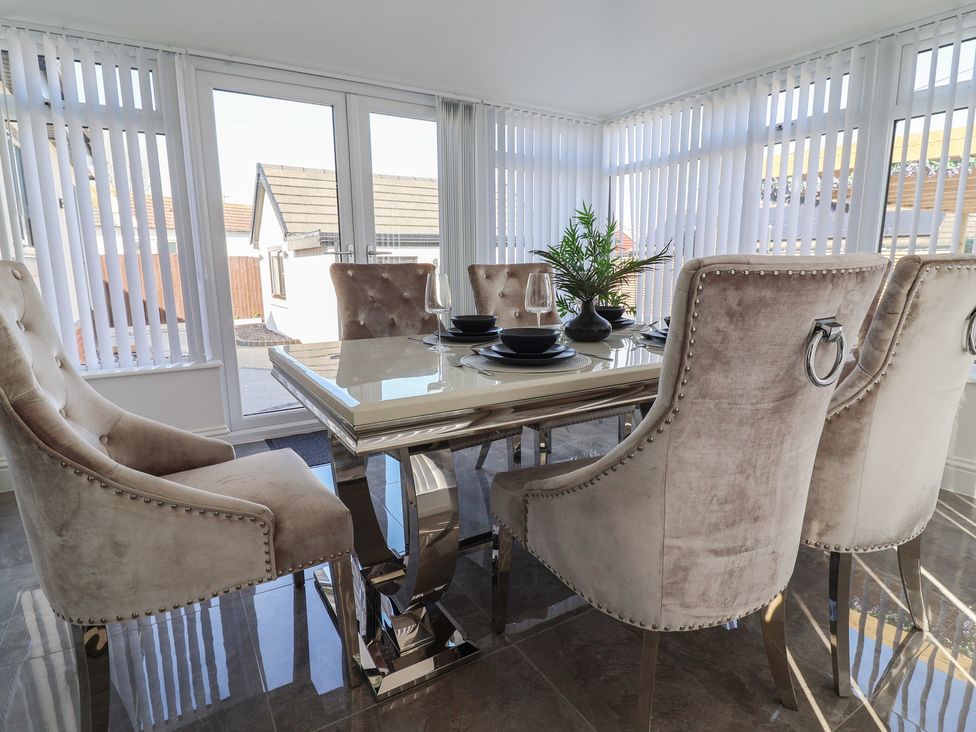 A dining room with a glass table and chairs at 1 Talbot Drive Talacre