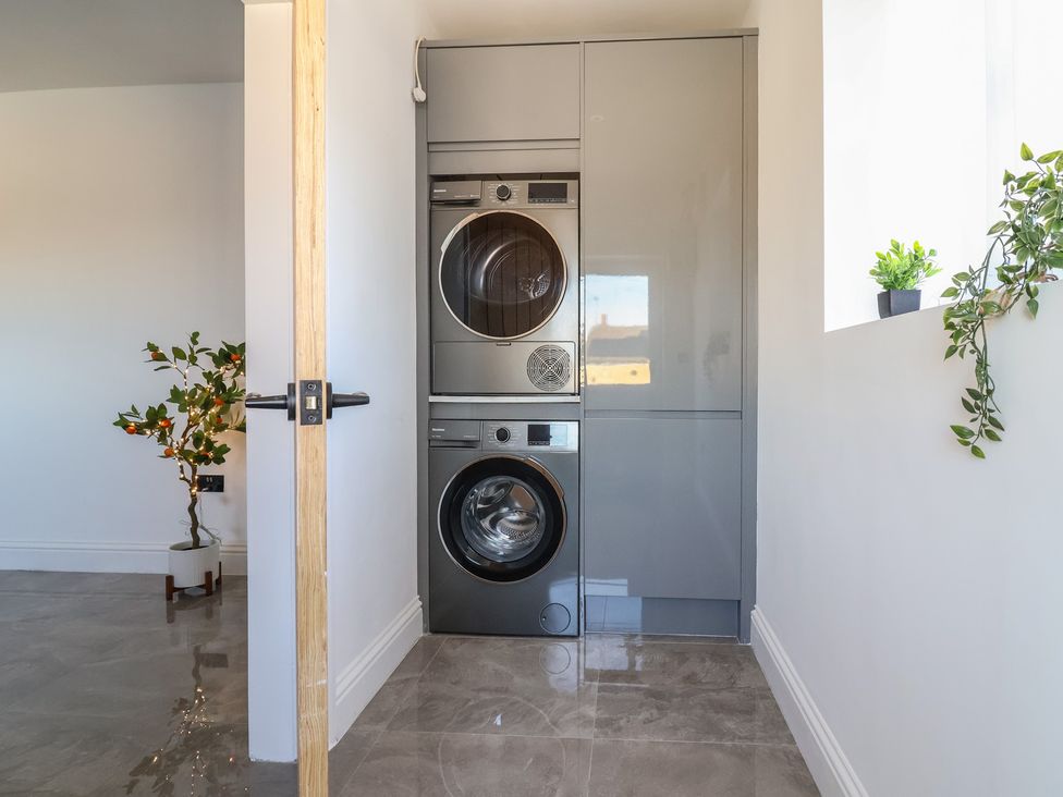 A laundry room featuring a stacked washing machine and tumble dryer at 1 Talbot Drive Talacre