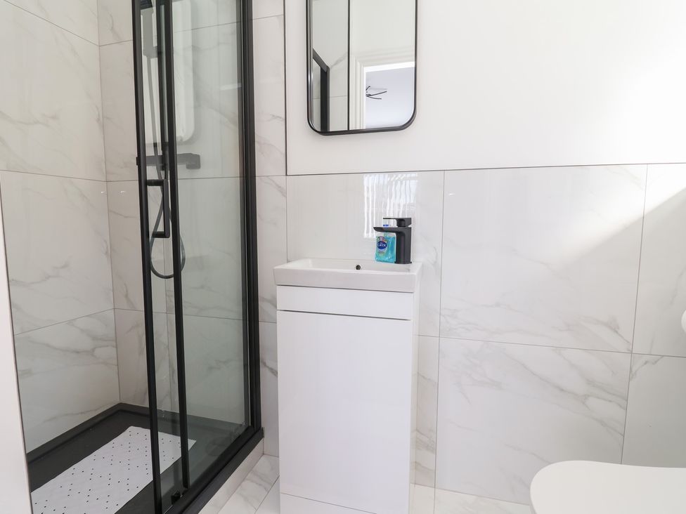 A bathroom with a shower, sink, and mirror at 1 Talbot Drive in Talacre
