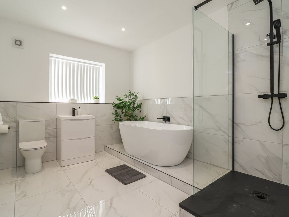 A bathroom with a bathtub, shower, toilet, and sink at 1 Talbot Drive, Talacre