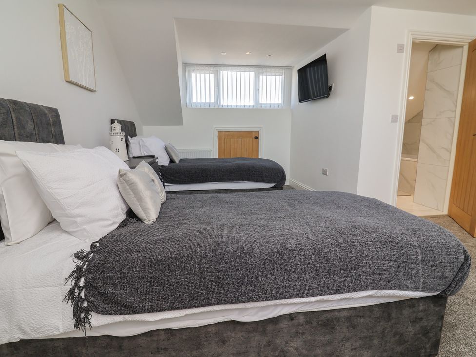 A bedroom with two beds and a TV on the wall at 1 Talbot Drive Talacre