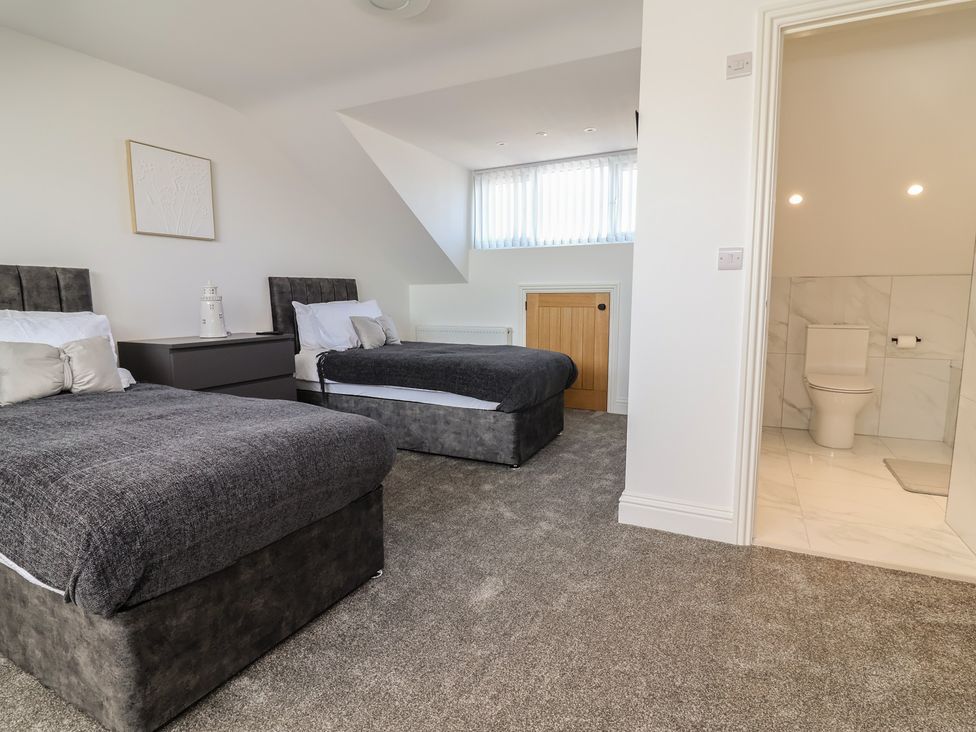 A bedroom with two beds and an adjacent bathroom at 1 Talbot Drive in Talacre